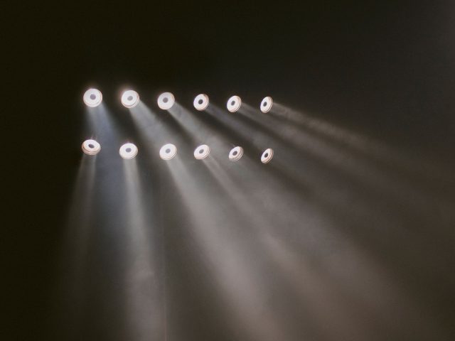 Rows of stage lighting fixtures beaming through haze